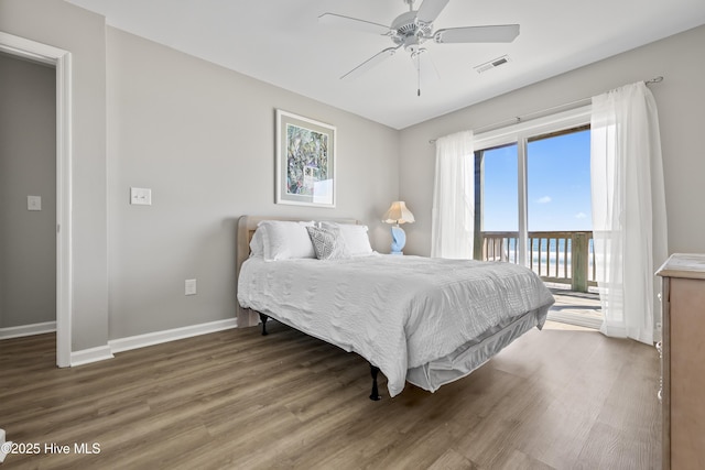 bedroom featuring visible vents, a ceiling fan, wood finished floors, baseboards, and access to exterior