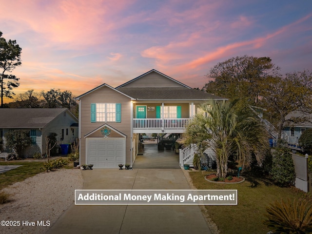 beach home with stairs, a garage, concrete driveway, a porch, and a carport