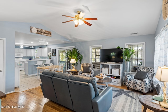 living room with light wood finished floors, visible vents, lofted ceiling, and a ceiling fan