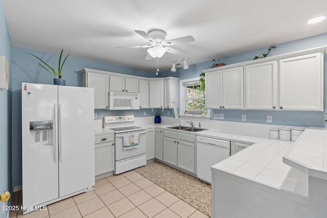 kitchen with a sink, tile counters, white appliances, white cabinets, and ceiling fan