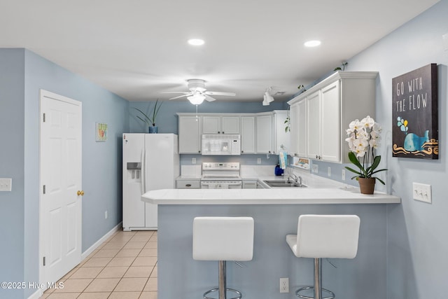 kitchen featuring light countertops, a sink, a ceiling fan, light tile patterned floors, and white appliances