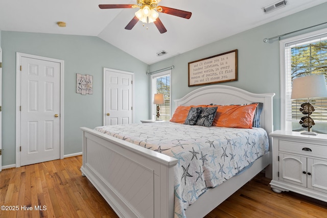 bedroom with light wood finished floors, visible vents, ceiling fan, and vaulted ceiling