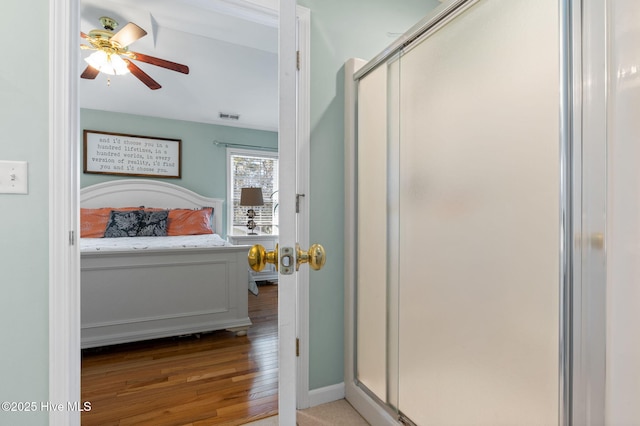 bathroom with a ceiling fan, a shower stall, wood finished floors, baseboards, and visible vents