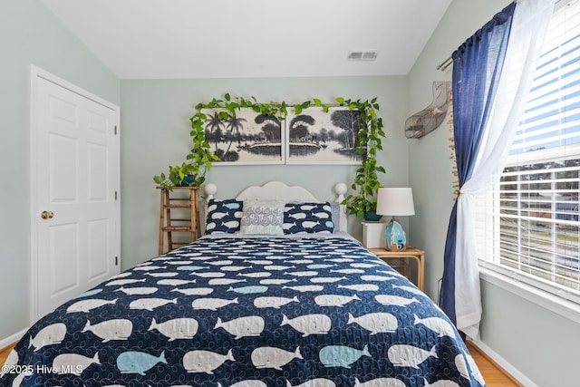 bedroom featuring baseboards, visible vents, and wood finished floors