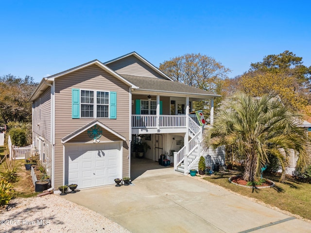 coastal home featuring stairs, driveway, a ceiling fan, an attached garage, and a porch