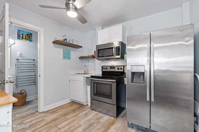 kitchen with a ceiling fan, light wood-type flooring, white cabinets, and stainless steel appliances