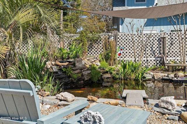 view of yard featuring a garden pond and fence