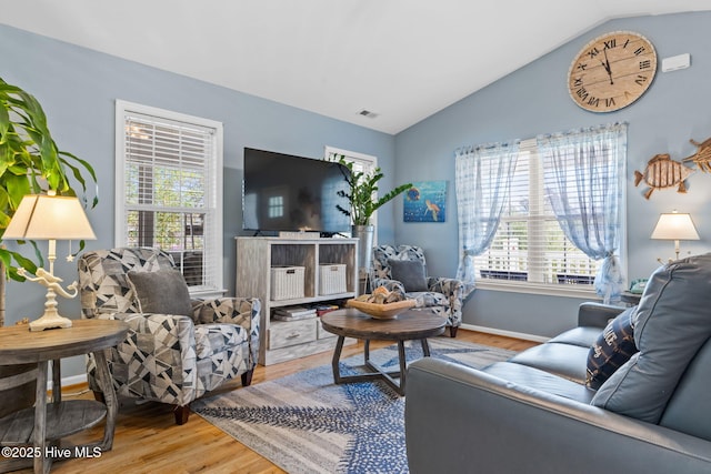 living room featuring plenty of natural light, lofted ceiling, and wood finished floors