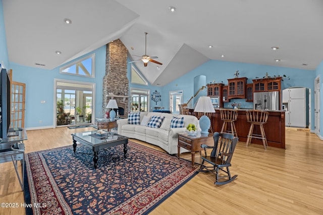 living room with visible vents, high vaulted ceiling, arched walkways, ceiling fan, and light wood-style floors