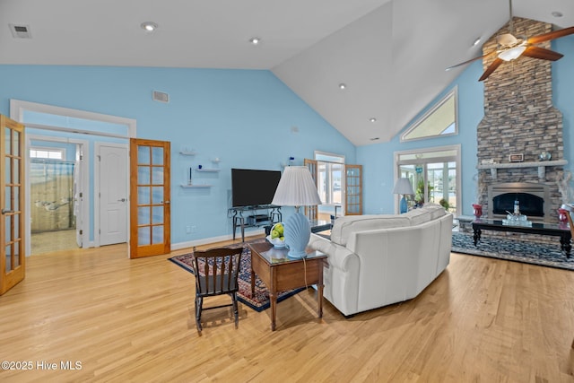 living room featuring light wood-type flooring, french doors, visible vents, and a fireplace