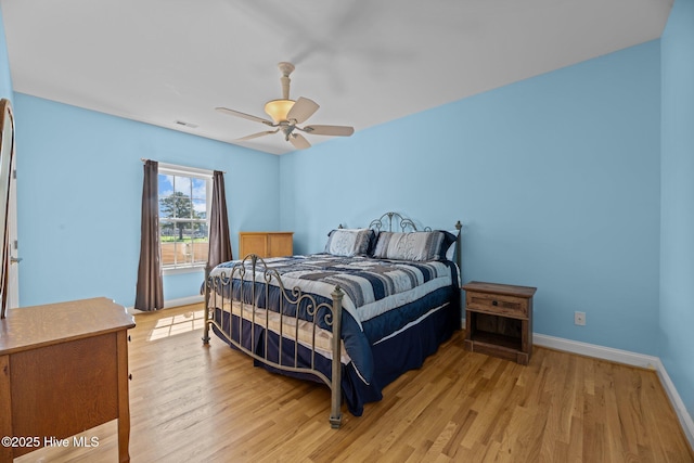 bedroom featuring a ceiling fan, visible vents, baseboards, and light wood-type flooring