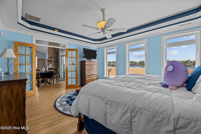 bedroom featuring french doors, a raised ceiling, and crown molding