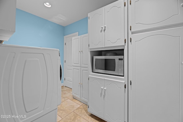 kitchen featuring stainless steel microwave, washer / clothes dryer, and white cabinetry