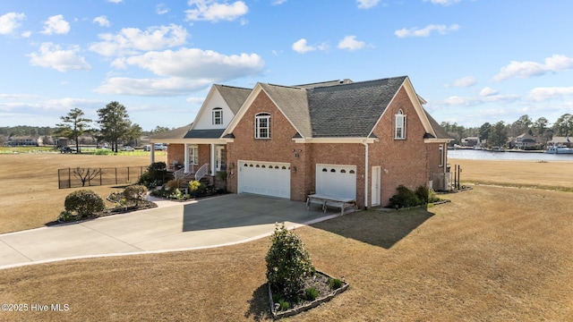 view of front of house featuring a water view, concrete driveway, a front yard, a garage, and brick siding