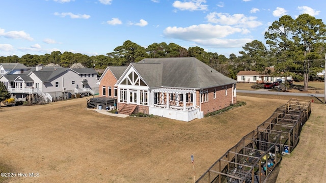 back of property featuring brick siding, a shingled roof, a lawn, and a pergola