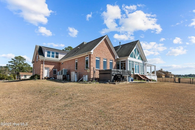 view of side of home with stairs, a lawn, brick siding, and a sunroom