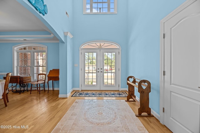 foyer entrance with baseboards, french doors, light wood-type flooring, and ornamental molding