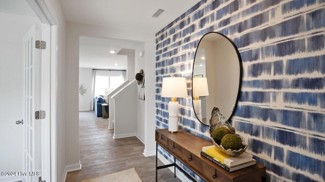 corridor featuring wood finished floors, visible vents, and baseboards