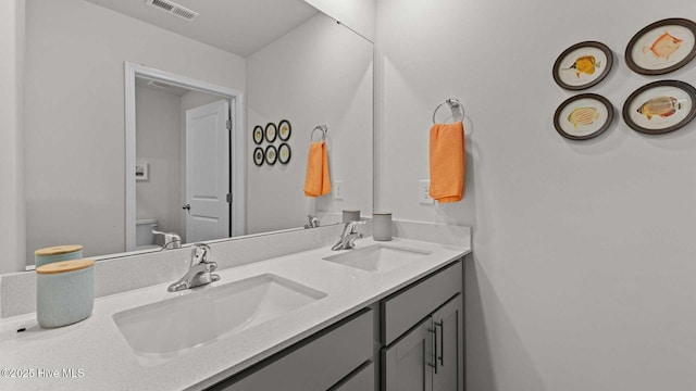 bathroom featuring a sink, visible vents, toilet, and double vanity