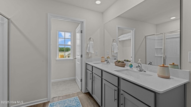 full bathroom featuring a sink, baseboards, wood finished floors, and double vanity