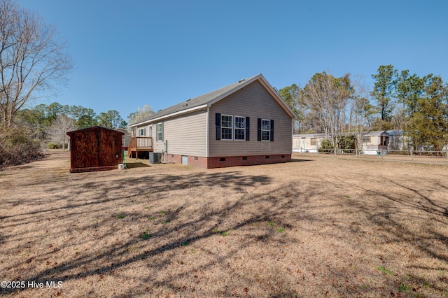 view of home's exterior with a storage unit, an outbuilding, fence, crawl space, and central AC unit