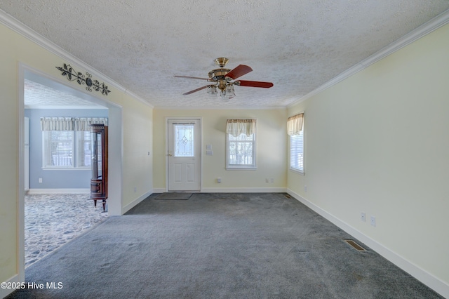 unfurnished room featuring dark carpet, a textured ceiling, a healthy amount of sunlight, and ornamental molding