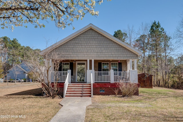 bungalow-style home featuring covered porch and a front lawn