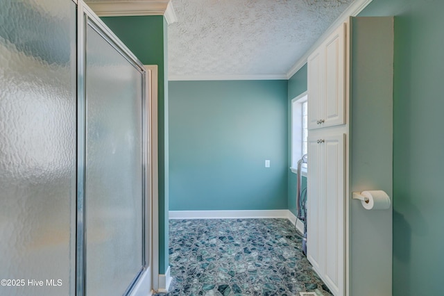 full bathroom featuring ornamental molding, baseboards, a stall shower, and a textured ceiling