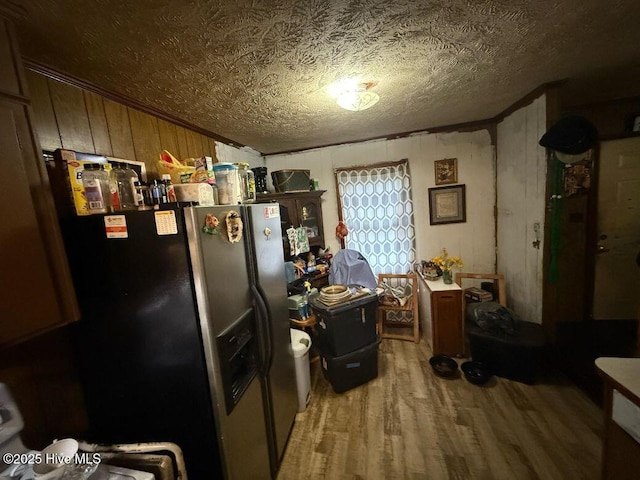 kitchen with wooden walls, stainless steel fridge, a textured ceiling, and wood finished floors