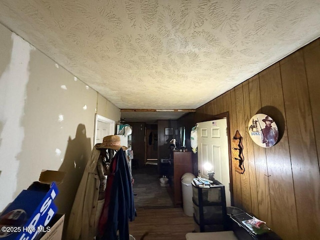 corridor featuring a textured ceiling, wood finished floors, and wood walls