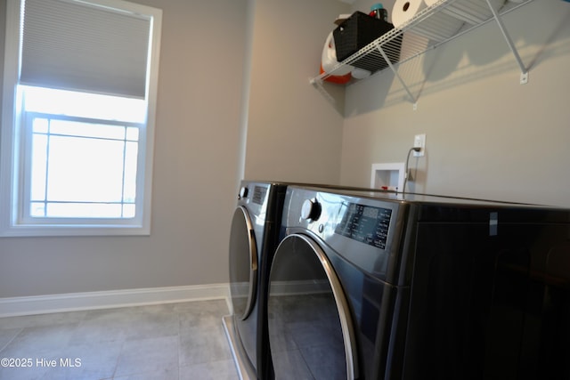 clothes washing area featuring laundry area, light tile patterned floors, baseboards, and washing machine and clothes dryer