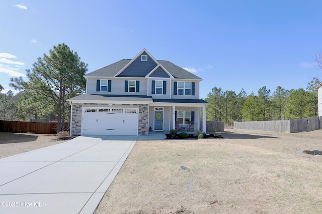 view of front of property featuring a garage, stone siding, driveway, and fence