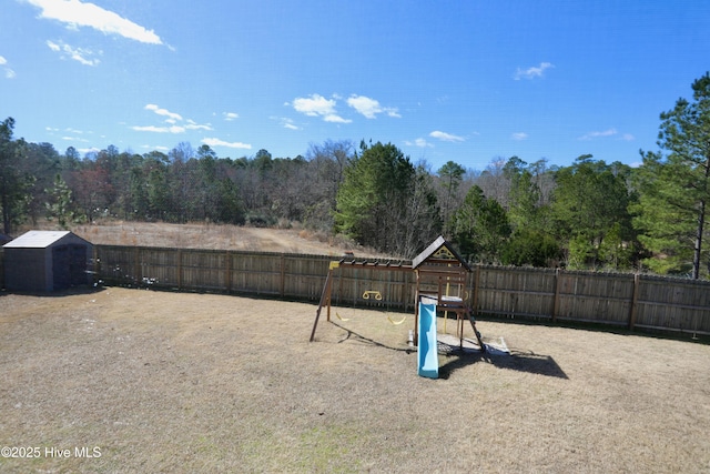 view of yard with fence, an outdoor structure, a shed, and a playground