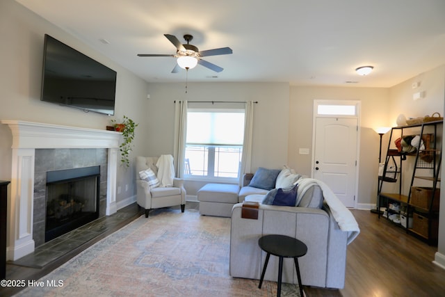 living room with a fireplace, baseboards, ceiling fan, and wood finished floors