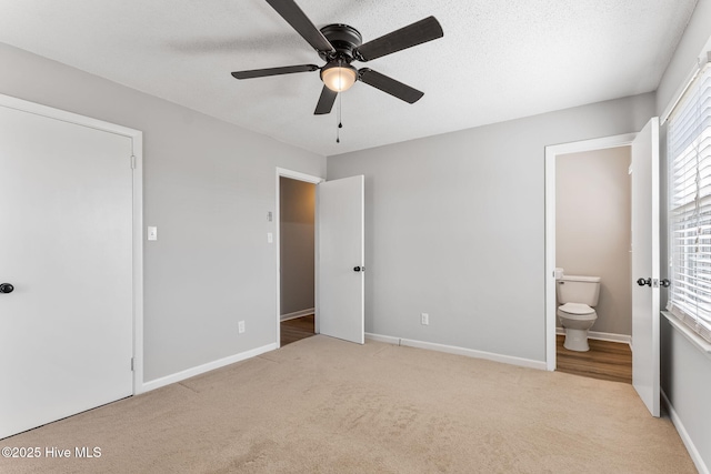 unfurnished bedroom with carpet, baseboards, ensuite bathroom, and a textured ceiling