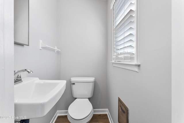 bathroom featuring wood finished floors, toilet, baseboards, and a sink