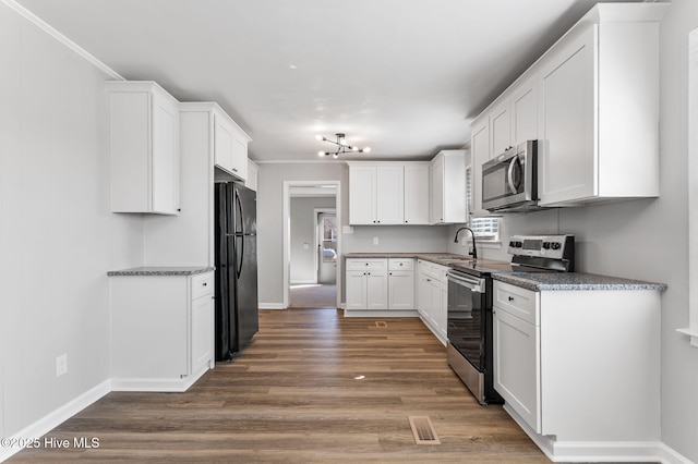 kitchen featuring crown molding, white cabinets, wood finished floors, and appliances with stainless steel finishes