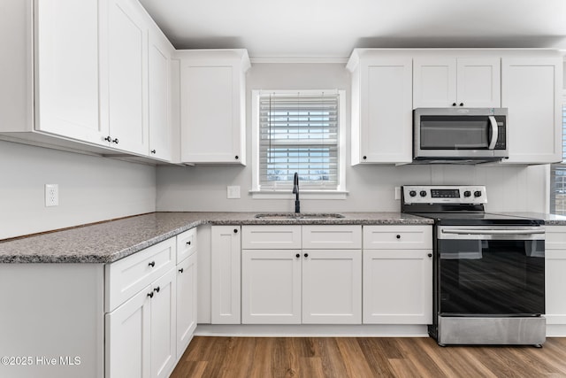 kitchen featuring crown molding, dark wood finished floors, appliances with stainless steel finishes, white cabinetry, and a sink