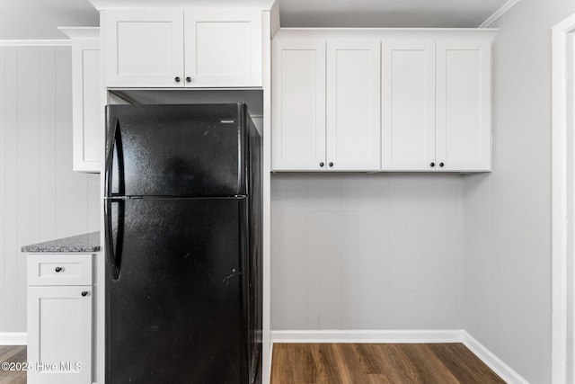 kitchen with light stone counters, baseboards, dark wood finished floors, freestanding refrigerator, and white cabinetry