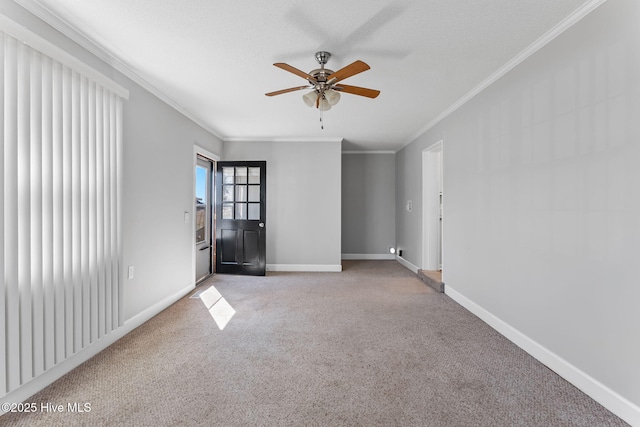 carpeted spare room with a textured ceiling, a ceiling fan, crown molding, and baseboards