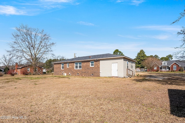 back of house with a lawn, brick siding, and crawl space