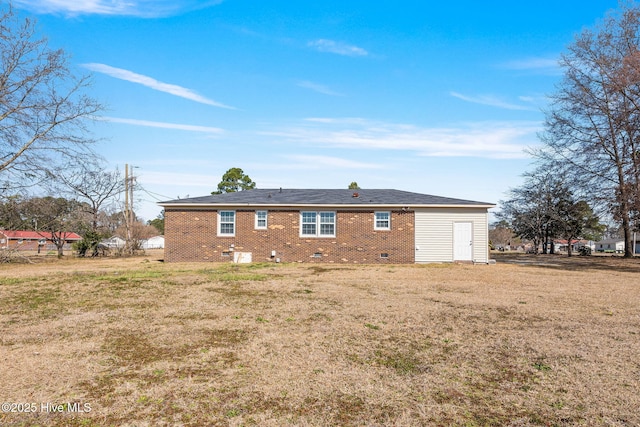 back of property featuring crawl space, brick siding, and a lawn