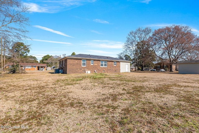 rear view of house featuring a lawn, brick siding, and crawl space