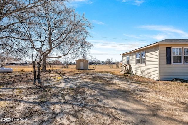 view of yard with an outbuilding, entry steps, a storage shed, and fence