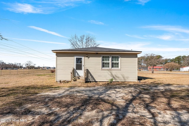 rear view of property featuring a lawn and entry steps