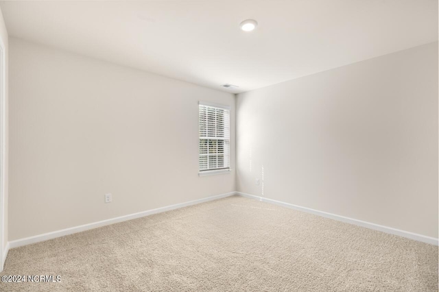 unfurnished room featuring light carpet and baseboards