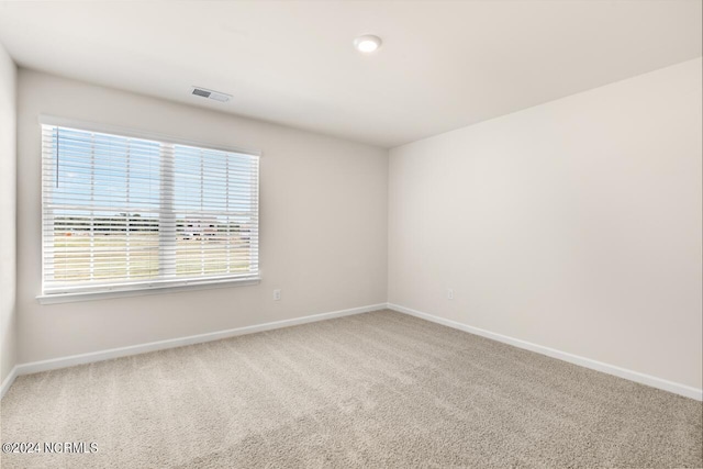 carpeted empty room featuring visible vents and baseboards