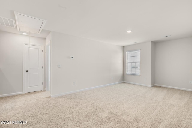 empty room featuring light carpet, visible vents, attic access, and baseboards