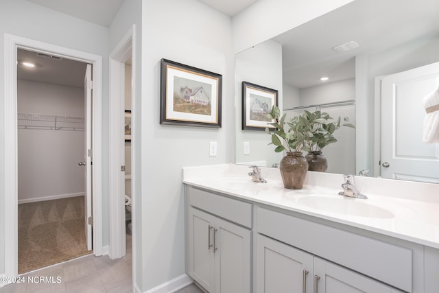 full bathroom featuring a sink, a walk in closet, visible vents, and double vanity