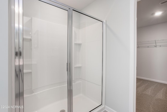 bathroom with visible vents, baseboards, a spacious closet, and a shower stall